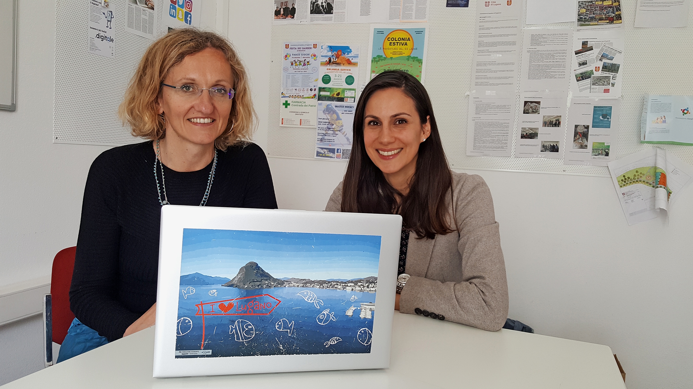 Monica Aliprandi, responsabile del progetto eQuiD presso i servizi della Divisione Socialità della Città di Lugano (a sinistra), ed Elena Marchiori di Lugano Living Lab davanti a un computer portatile in stile eQuiD.